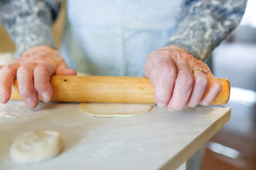 Roll the dough with a rolling pin. An old woman is cooking. For a dough dish