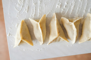 Raw manti lying on the table has just been blinded. A dish of dough. Grandma's recipe