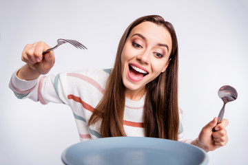 Hungry lady holding fork and spoon can't wait to start eating wear striped pullover isolated white...