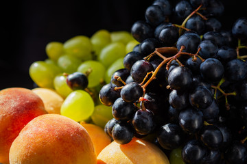 Purple and green grapes and orange peaches