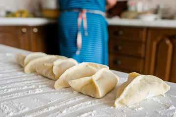 Ready manti, dumplings at the grandmother's kitchen. An old woman is preparing a dish of dough.
