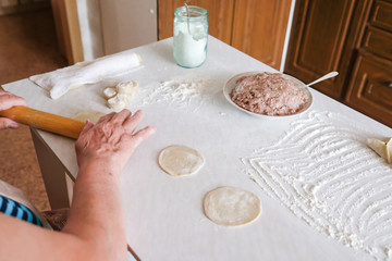 Old woman sculpts pasta. Grandma makes manti. Recipe for meat and dough.