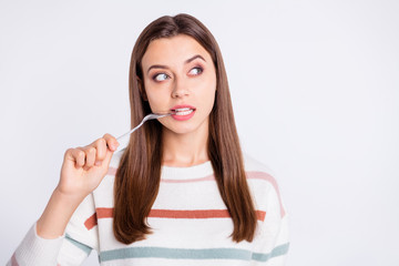 Hungry lady holding spoon into mouth want to know what is on supper wear striped pullover isolated...