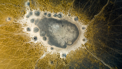 Straight-down aerial view onto an African waterhole in Botswana, Okavango Delta, surrounded by animal tracks in the dry season - obrazy, fototapety, plakaty