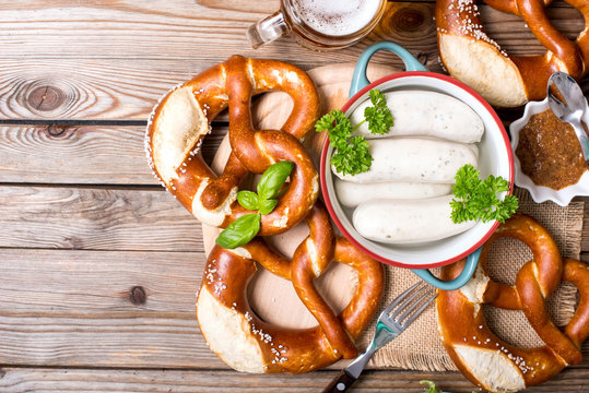Pretzels, white bavarian sausages, beer and mustard on wooden background, german traditional food, oktoberfest