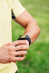 cropped view of sportsman touching fitness tracker outside
