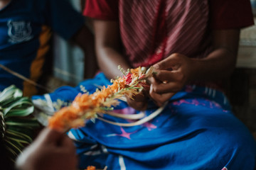 woman weaving Fijian garland