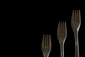 metal forks on a black background. top view on stainless forks with copy space