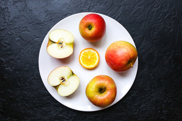 Apples lying on the white plate. Still life photo. Black background.