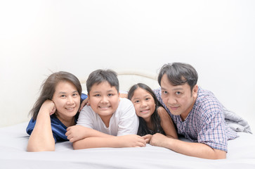 Asian Happy young family lying in bed together