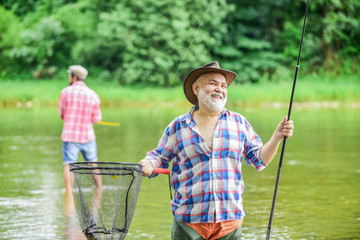 Activity and hobby. Happy cheerful people. Master baiter. Fisherman with fishing rod. Fishing freshwater lake pond river. Bearded men catching fish. Mature man with friend fishing. Summer vacation