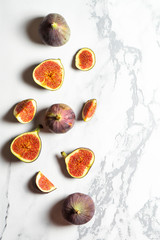 Top view fresh exotic cutted on half fig on marble table. Food photo background. Creative scheme of the whole and sliced figs. Flat lay. View from above. Tasty summer fruit