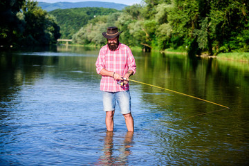 Fototapeta na wymiar mature bearded man with fish on rod. big game fishing. relax on nature. successful fisherman in lake water. hipster fishing with spoon-bait. fly fish hobby. Summer fishery activity. real professional