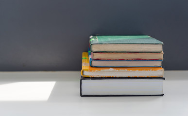 Books stacked on the table in library at university in selective focus.