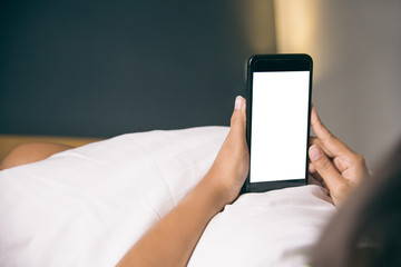 Asian Woman's hands using smartphone with blank screen in bedroom at morning.