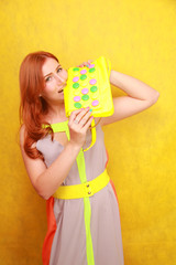 pretty redheaded girl in bright summer dress with yellow bright leather bag