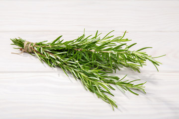 Fresh Rosemary twig on white wooden background