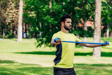 handsome bearded man holding suspension straps while exercising in park