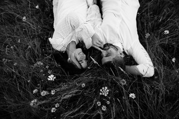 man and woman are liying  on the grass in mountains black and white