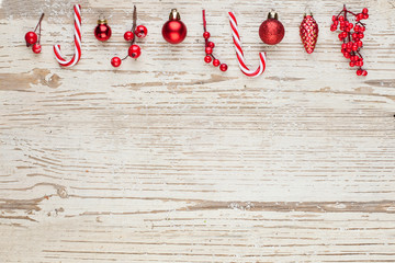 Christmas composition border on white wooden background. Red holly berries, baubles and candy....