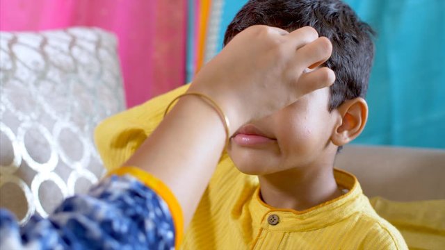 Raksha Bandhan - Sister of a cute little boy applies rice on the tilak . 