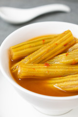 Vegetable of drumstick tree in spicy curry with coconut milk, in white bowl on concrete table.