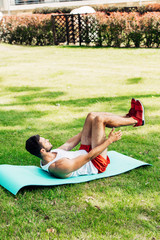 handsome man in sportswear doing do abs on fitness mat outside © LIGHTFIELD STUDIOS