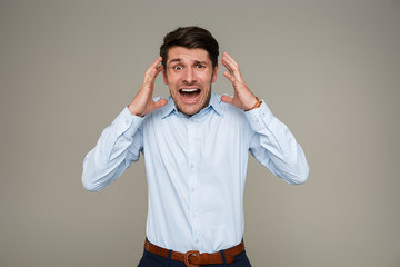 Image of frightened young man wearing formal clothes screaming at camera and throwing up hands