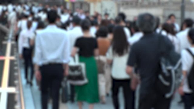 UMEDA, OSAKA, JAPAN - CIRCA JULY 2019 : Blurred view of crowd of people walking down the street in busy rush hour. Many commuter walking near Osaka train station after work. Shot in early evening.