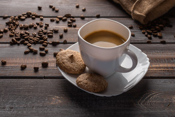 Cup of coffee and biscuits on a linen napkin. Coffee beans and bag