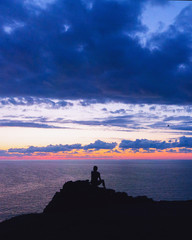 una persona sola quarda il tramonto al mare