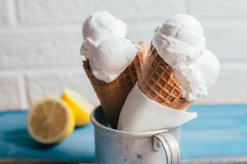 studio shoot of delicious vanilla and lemon ice cream in cone on blue wooden board