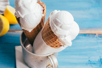 studio shoot of delicious vanilla and lemon ice cream in cone on blue wooden board