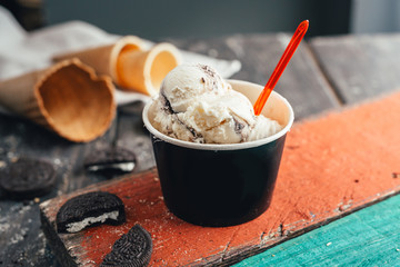 tasty ice cream in paper cup on green and red wooden table