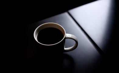 Obraz na płótnie Canvas Black coffee cup on black modern table background with sunlight.