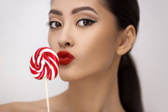 Fashion Portrait of Asian Woman with Lollipop in Studio