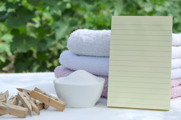Wooden clothespins, bowl of laundry powder, stack of clean towels and blank  cleaning list