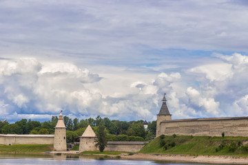 A very beautiful photo of the Pskov Kremlin on the banks of the Pskov river with beautiful flowers in the foreground. The pearl of the Russian North. An ancient fortress.