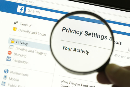 Hand holding a magnifying glass and magnifying the word "Privacy settings"