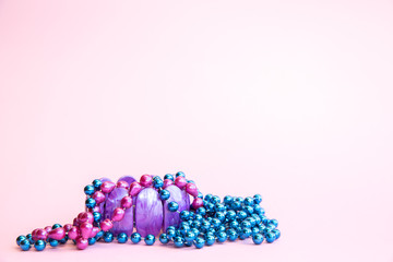 Purple bracelet and beads of different colors on a pink background.