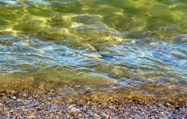 Soft rippling wave covering tiny pebbles and stones 