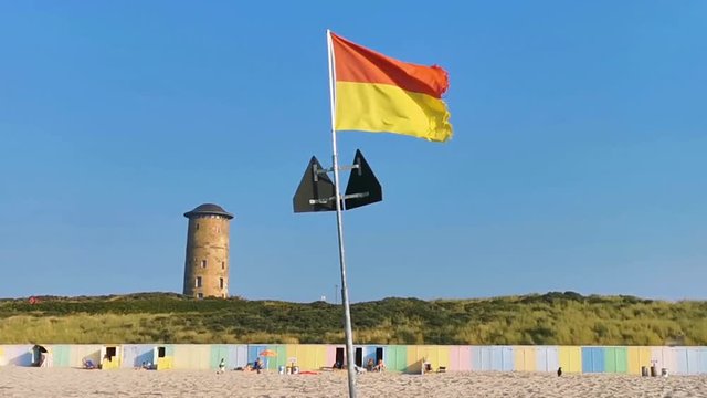 the beach of domburg with a red and yellow waving flag, touristic coastal city in zeeland, the Netherlands