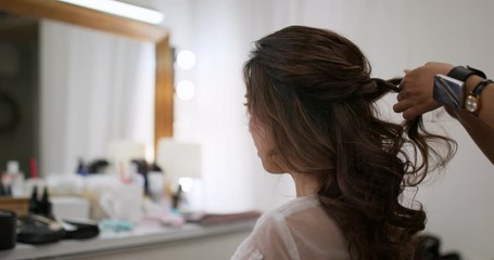 Hair stylist makes hair for bride in beauty salon