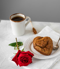 homemade heart shaped cake, on a white plate, red rose, cup of coffee, light backdrop
