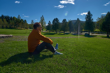 30-year-old man resting outdoors sitting on the grass on a camping trip, in Quebec, Harrington. Travel to Canada