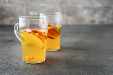 Two glass cups with apple tea on grey background