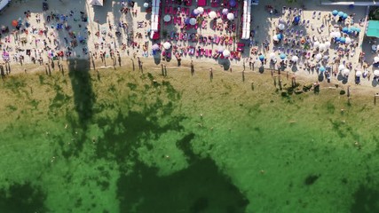 Aerial timelapse top view of a beach life during sunny summer day. A lot of people swimming in water