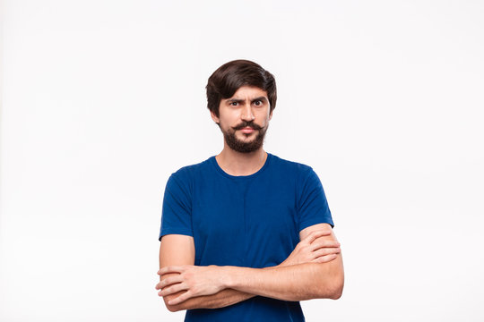 Good looking brunet man in a blue shirt holding arms folded over his chest with sceptical emotion standing isolated over white background.