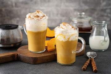 Two glass cups with spice pumpkin cappuccino on dark grey background
