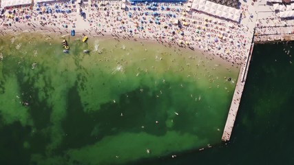 Aerial timelapse top view of a beach life during sunny summer day. A lot of people swimming in water